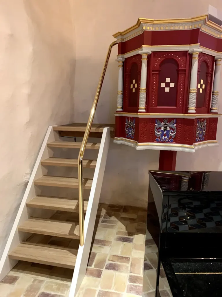 Et gelænder i messing som leder op til en prædikestol