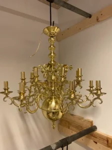 en stor lysekrone i messing med skjulte fatninger